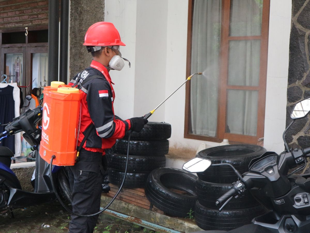 Pest control technician spraying the exterior of a building