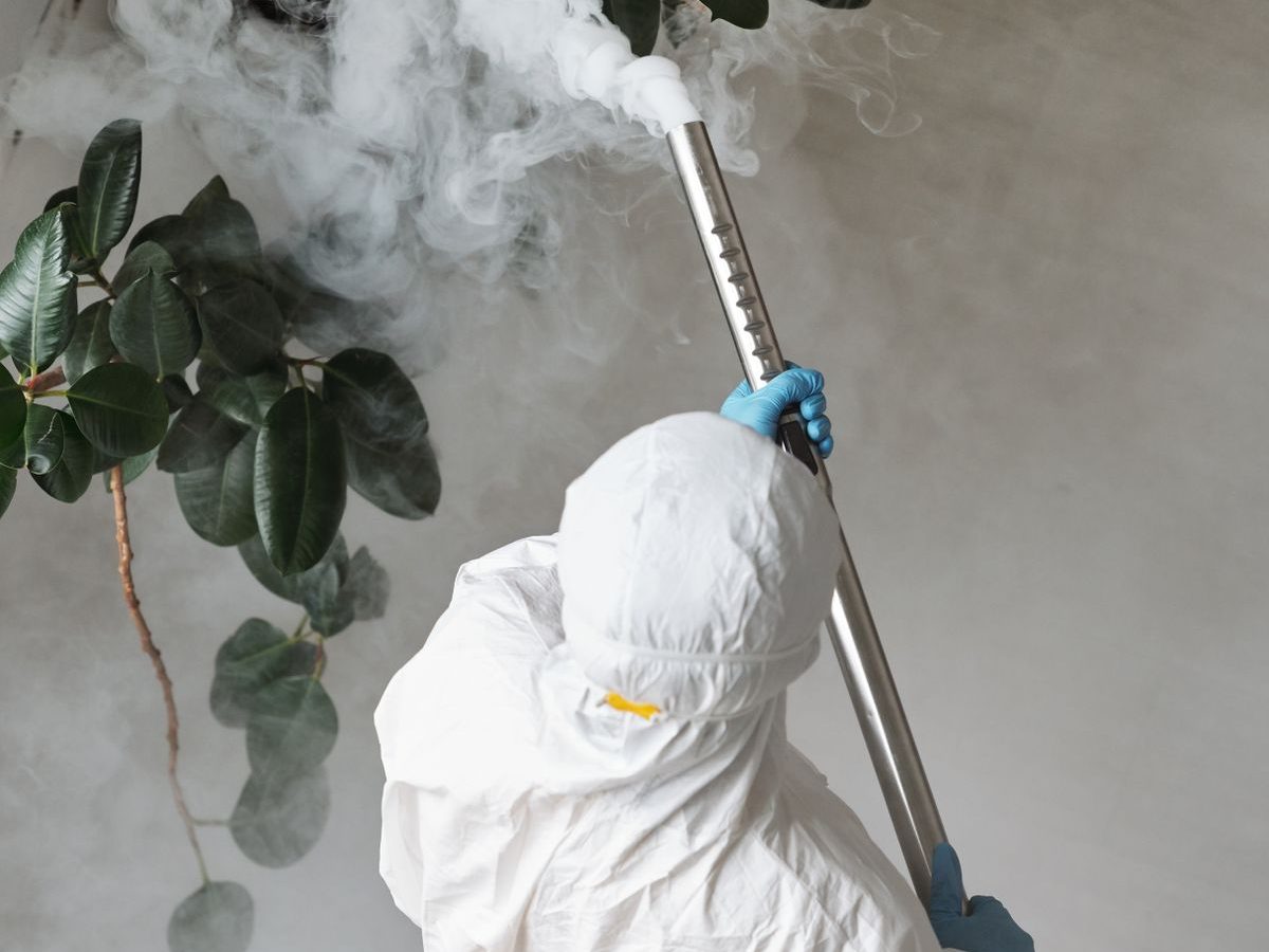 Technician in protective gear treating an interior