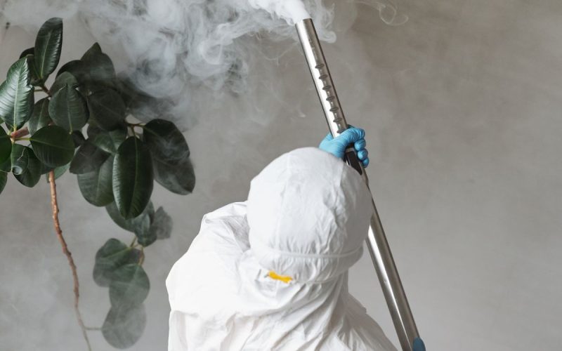 Technician in protective gear treating an interior